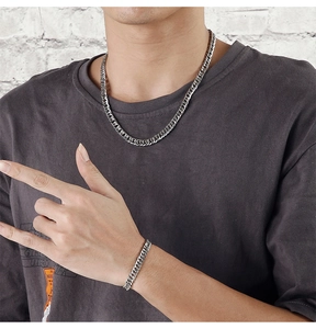 Male model wearing chunky silver stainless steel Cuban link necklace and bracelet set
