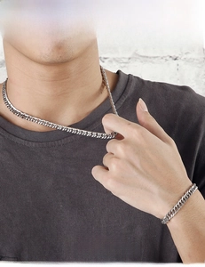 Close-up of men's chunky silver stainless steel Cuban link necklace and bracelet set