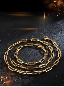 Polished gold stainless steel paperclip chain necklace and bracelet set on black background