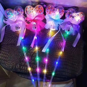 Primo piano di bacchette magiche a forma di cuore con luci LED colorate e nastri di seta