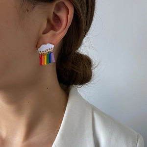 Detalle de pendientes de nube con borlas de arcoíris usados por modelo en estilo minimal