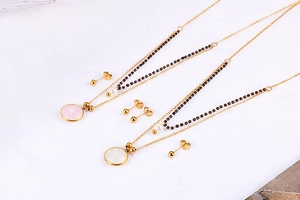 Detail of gold layered necklaces with pink and white pendants and ball stud earrings