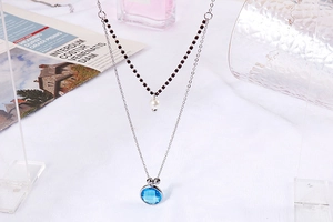 Detailed view of silver double-layer necklace with blue gem, red beads, and pearl pendant