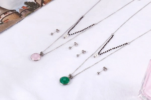 Detailed set of silver necklaces with pink and green crystal pendants and matching studs