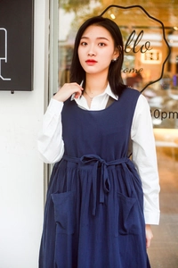 Detail view of dark blue cotton apron featuring large front pockets and waist tie closure