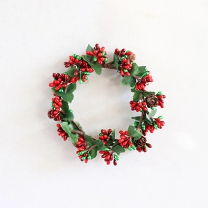 Christmas wreath with red berries, green leaves and pine cones on a light background