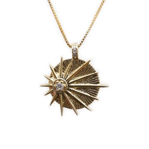 Golden sun pendant necklace with micro-paved cubic zirconia and evil eye detail on white background