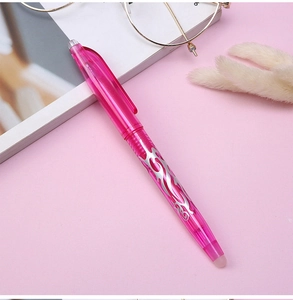 Pink erasable gel pen with silver tribal patterns on a desktop with accessories