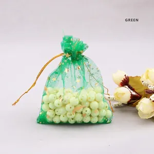 Grass green organza jewelry bag with gold stars and drawstring closure on grey surface