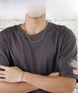 Close-up of a stainless steel curb chain necklace and bracelet set on a male model