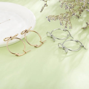 Boucles d'oreilles créoles à nœud minimalistes en or et argent sur un plateau