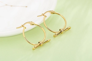 Détail de boucles d'oreilles créoles dorées avec nœud et finition polie brillante