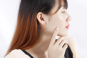 Détail d'un mannequin portant des créoles dorées avec nœud au style minimaliste