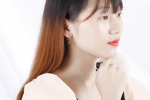 Détail d'une femme portant d'élégantes créoles dorées nouées sur un fond lumineux