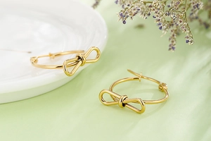 Détails macro de boucles d'oreilles créoles dorées en forme de nœud poli sur fond
