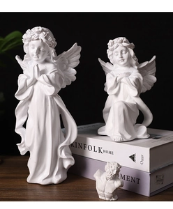 Close-up of elegant white resin angel sculptures with smooth texture on wooden surface