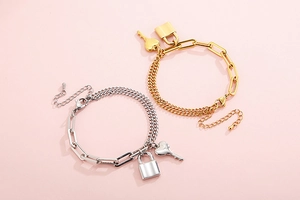 Detail view of gold and silver chunky chain bracelets with heart key and lock charms