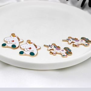 Golden alloy unicorn enamel charms set of four on white plate with silk background