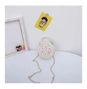 Close-up of white woven child crossbody bag with 3D floral and pearl decorations