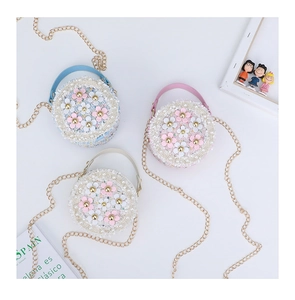 Detail of tweed round crossbody bags with 3D floral accents and pearl chain straps