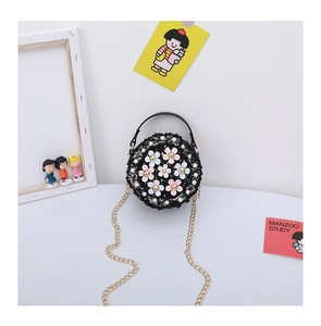 Detail of round black tweed crossbody bag featuring 3D flowers and gold chain strap