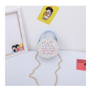 Detail of round blue tweed girl's purse with 3D floral accents and golden chain strap