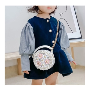 Detail of child's round crossbody bag with 3D flowers and golden chain strap