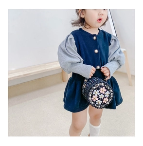 Detail of navy puff sleeve dress with pearl buttons and floral round crossbody bag