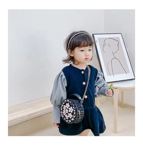 Detailed view of girls navy blue dress with a black tweed flower crossbody bag on model