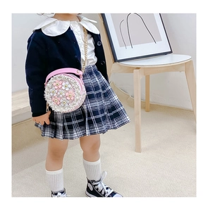 Close-up of pink crossbody bag with 3D flowers and pearls worn by a child model