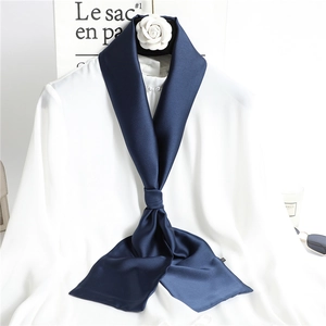 Solid navy blue skinny silk scarf tied on a white shirt with elegant lifestyle props