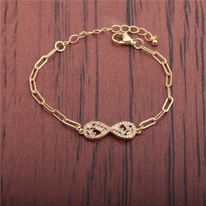 Goldenes Unendlichkeitsarmband mit Mikrozirkonia und Gliederkette auf einer Holzoberfläche