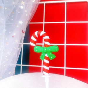 Christmas candy cane cake topper with red and white stripes and a green polka dot bow