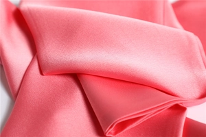 Close-up of the smooth pink faux silk fabric texture and glossy finish of the narrow scarf