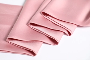 Close-up of soft pink satin fabric with smooth texture and elegant drape detail