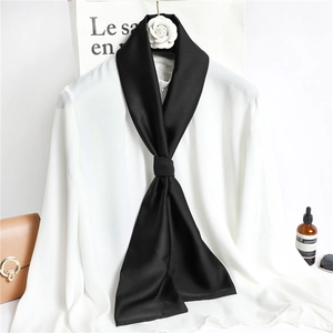 Detailed close-up of a long black satin scarf elegantly knotted on a white shirt