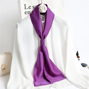 Detailed view of a purple silk scarf knotted on a white shirt with fashion accessories