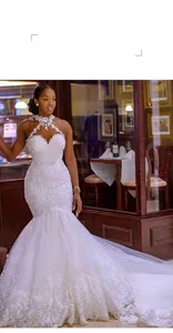 Dettaglio squisito dell'abito da sposa a sirena bianco con collo a lupetto in pizzo ricamato