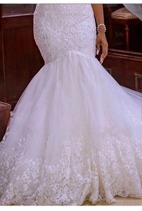 Dettaglio dell'abito da sposa a sirena con applicazioni floreali in pizzo e gonna in tulle
