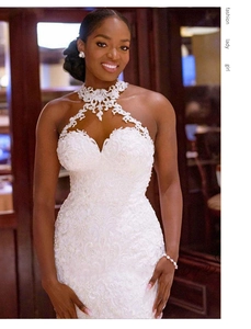 Dettaglio dell'abito da sposa in pizzo bianco con scollo all'americana e ricami floreali