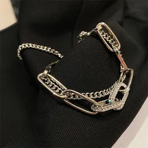 Vista macro di un bracciale a catena argentato con zirconi incastonati su tessuto nero
