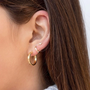 Detail of lightning bolt stud and gold hoop earrings set worn by a female model
