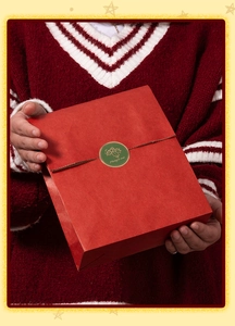 Scatola regalo di Natale rossa con etichetta Merry Xmas tenuta davanti a un maglione