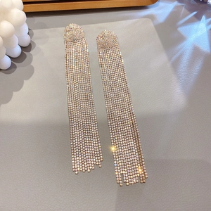 Macro shot of sparkling rhinestone tassel earrings on a textured grey background