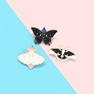 Detailed view of three enamel butterfly and moth brooches with mystical moon and star motifs