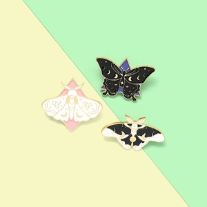 Detail of gothic moth and butterfly enamel pins with moon and geometric pattern details