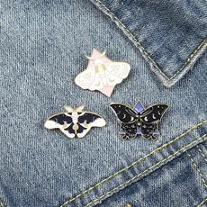Detailed enamel moth brooches with celestial moon and star patterns on denim jacket