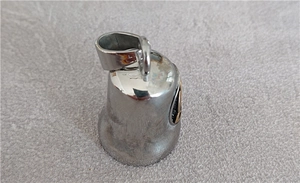 Close-up of polished silver Viking bell pendant with circular emblem on textured fabric