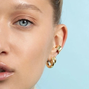 Gold plated geometric hoop earrings and ear cuff set shown on model on light blue background