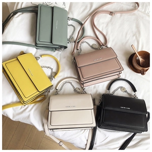 Flat lay of colorful leather flap handbags with chain straps and top handles on white fabric
